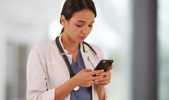 A female doctor texting on a smartphone