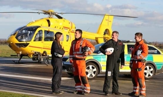 Paramedics with East Anglian Air Ambulance (EAAA) pose next to a helicopter