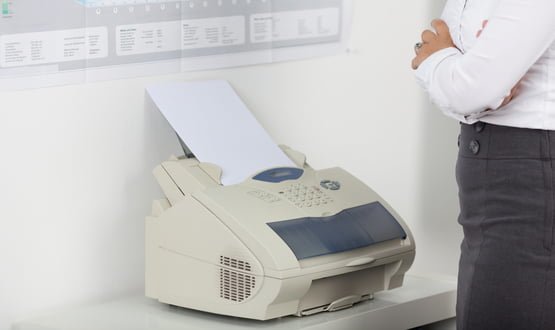 A businesswoman uses a fax machine