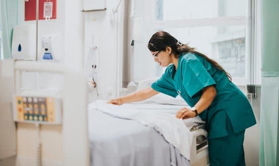 A nurse tending to a bed at a hospital