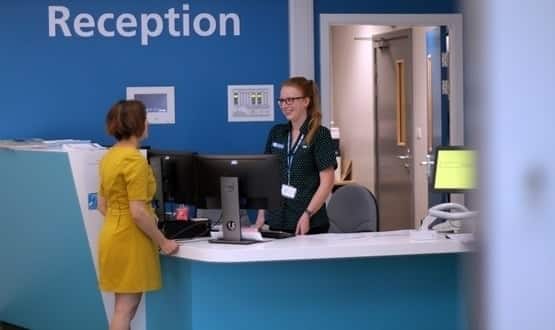Healthcare staff speaks to a female patient at the reception of Sheffield Teaching Hospitals
