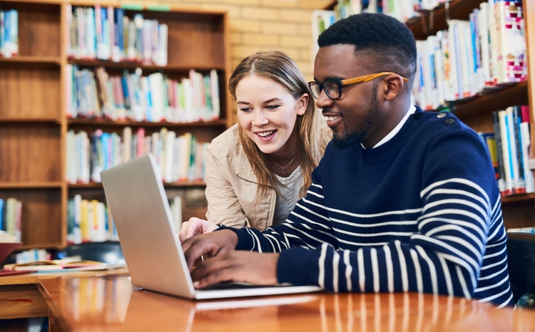 man and woman use laptop in library